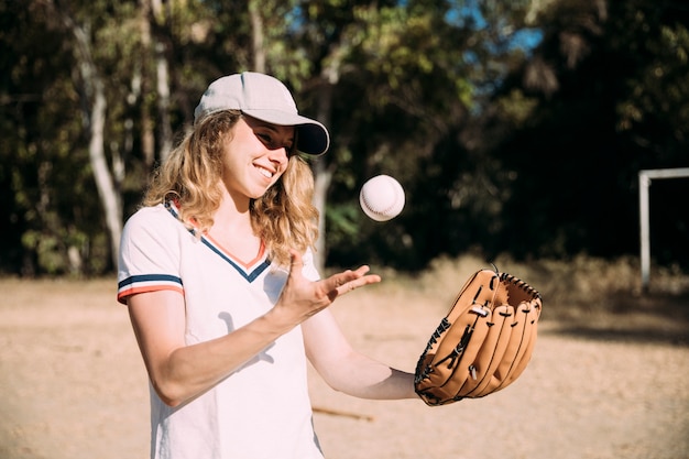 Glückliches jugendlich Mädchen, das Baseball spielt