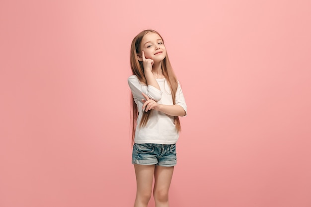 Glückliches jugendlich Mädchen stehend, lächelnd isoliert auf trendigem rosa Studio