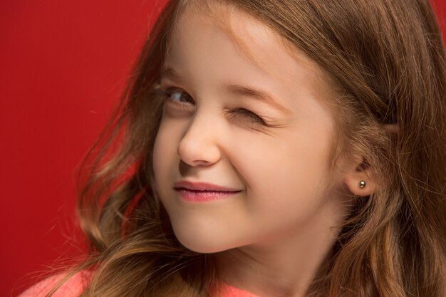 Glückliches jugendlich Mädchen stehend, lächelnd lokalisiert auf trendigem rotem Studiohintergrund.