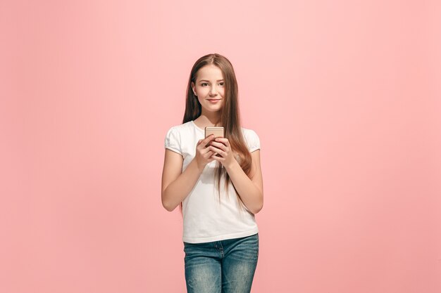 Glückliches jugendlich Mädchen stehend, lächelnd mit Handy über trendigem rosa Studio