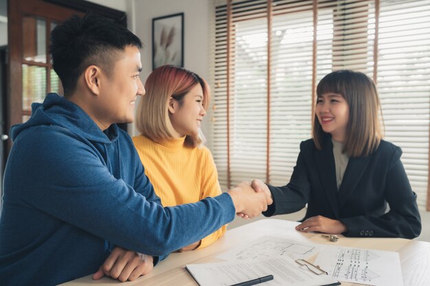 Glückliches junges asiatisches Paar und Grundstücksmakleragent