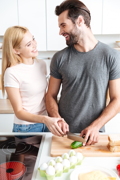 Glückliches junges liebendes Paar, das an der Küche steht und kocht
