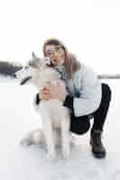 Kostenloses Foto glückliches junges mädchen, das mit siberian husky hund im winterpark spielt