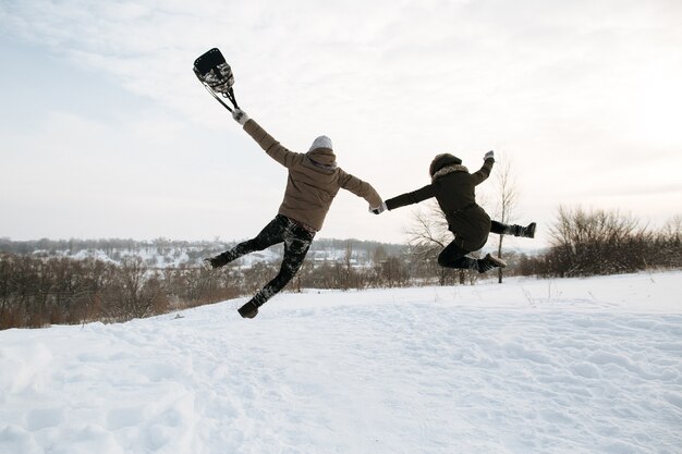 Glückliches junges Paar in der Liebe springt für Freude. Kalter Tag des verschneiten Winters. Winter Liebesgeschichte.