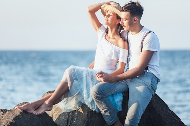 Glückliches junges romantisches Paar, das am Strand entspannt und den Sonnenuntergang beobachtet