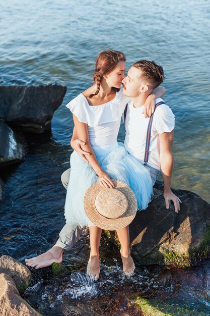 Glückliches junges romantisches Paar, das am Strand entspannt und den Sonnenuntergang beobachtet