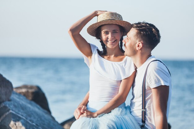 Glückliches junges romantisches Paar, das am Strand entspannt und den Sonnenuntergang beobachtet