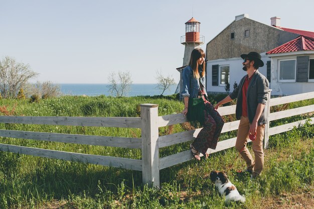 Glückliches junges stilvolles Hipster-Paar in der Liebe, die mit Hund in der Landschaft geht