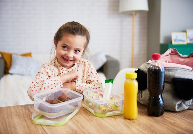 Glückliches Kind, das Brotdose mit Süßigkeiten zubereitet preparing