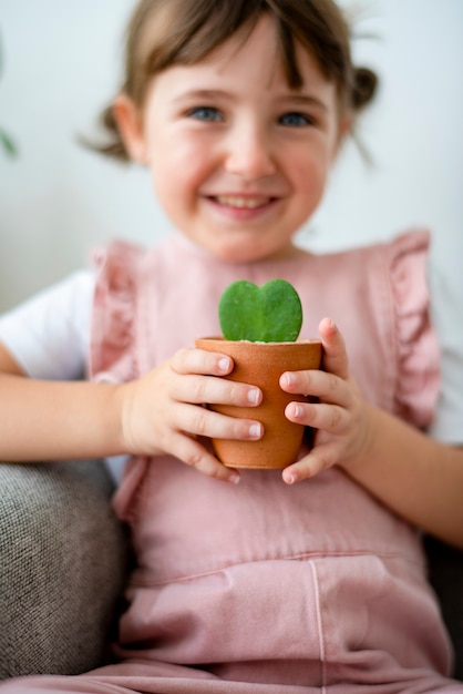 Glückliches Kind, das eine kleine Topfpflanze hält