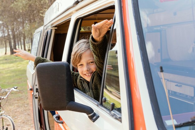 Glückliches Kind der Seitenansicht, das auf Fenster schaut