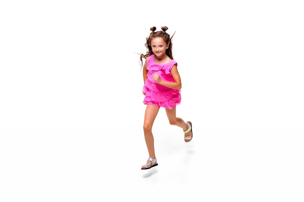 Glückliches Kind, kleines und emotionales kaukasisches Mädchen, das isoliert auf weiß springt und läuft