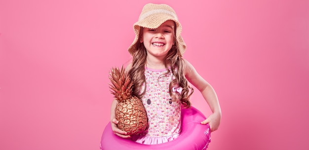 glückliches Kind mit Ananas auf farbigem Hintergrund