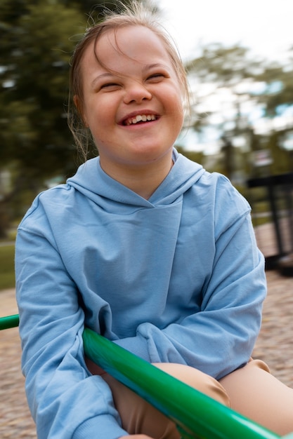 Kostenloses Foto glückliches kind mit down-syndrom, das draußen spielt