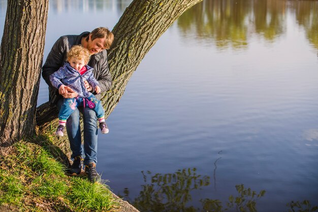 Glückliches Kind sitzt auf den Beinen seines Vaters