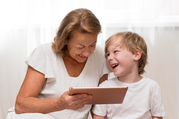Glückliches Kind und Oma mit Tablette
