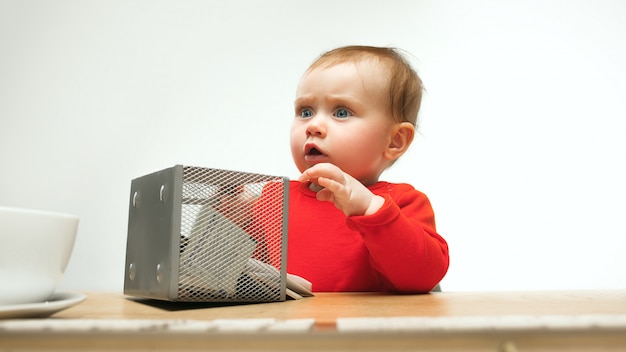 Glückliches Kindbaby-Kleinkind, das mit Tastatur des Computers lokalisiert auf einem weißen Hintergrund sitzt