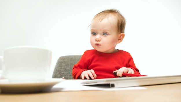 Glückliches kindbaby-kleinkind, das mit tastatur des computers lokalisiert auf einem weißen sitzt