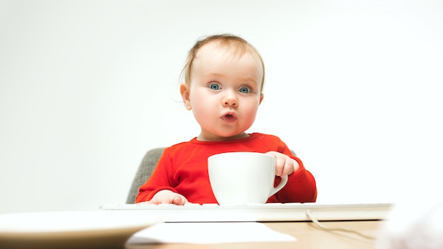 Glückliches Kindbaby-Kleinkind, das mit Tastatur des Computers lokalisiert auf einem weißen sitzt