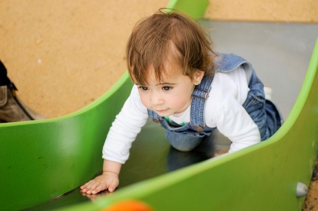 Glückliches kleines Mädchen, das auf einem städtischen Spielplatz spielt.