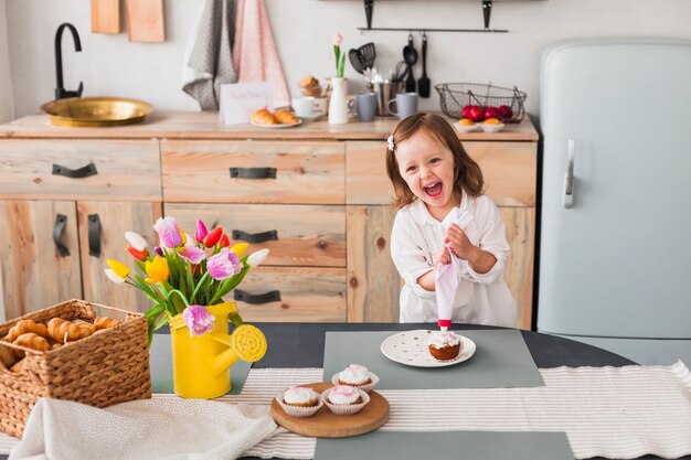 Glückliches kleines Mädchen, das kleinen Kuchen macht