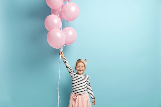 Glückliches kleines Mädchen, das Luftballons hält