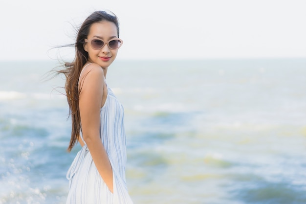 Kostenloses Foto glückliches lächeln der schönen jungen asiatischen frau des porträts entspannen sich um neary strand und meer