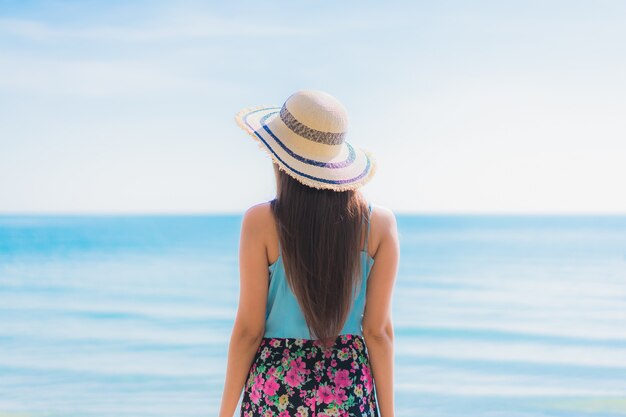 Glückliches Lächeln der schönen jungen asiatischen Frau des Porträts entspannen sich um Strandozean und -meer