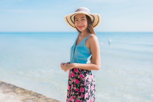 Glückliches Lächeln der schönen jungen asiatischen Frau des Porträts entspannen sich um Strandozean und -meer