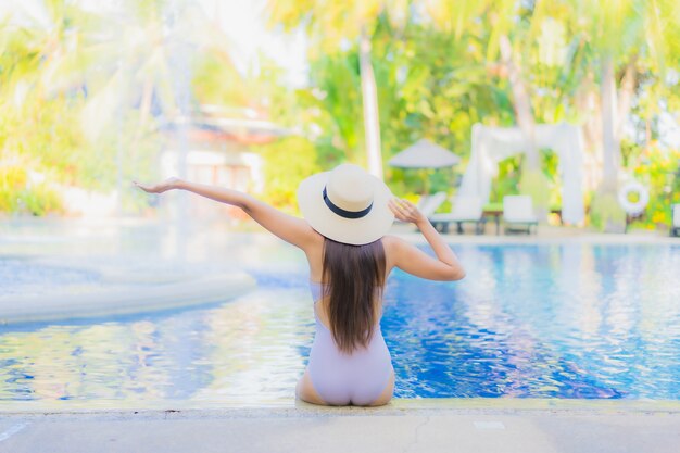 Glückliches Lächeln der schönen jungen asiatischen Frau des Porträts entspannen sich um Swimmingpool im Freien