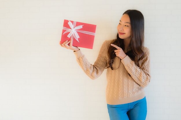 Glückliches Lächeln der schönen jungen asiatischen Frau des Porträts mit Geschenkbox