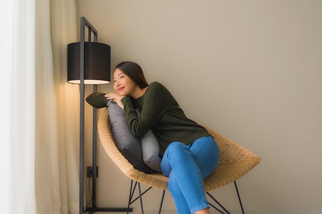 Glückliches Lächeln der schönen jungen asiatischen Frauen des Porträts entspannen sich das Sitzen auf Sofastuhl