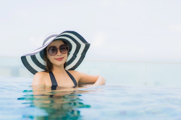 Glückliches Lächeln der schönen jungen asiatischen Frauen des Porträts entspannen sich Swimmingpool im Freien im Erholungsort