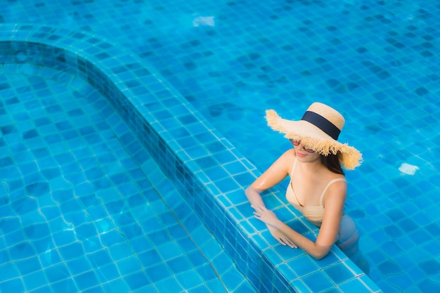 Glückliches Lächeln der schönen jungen asiatischen Frauen des Porträts entspannen sich Swimmingpool im Freien im Erholungsort