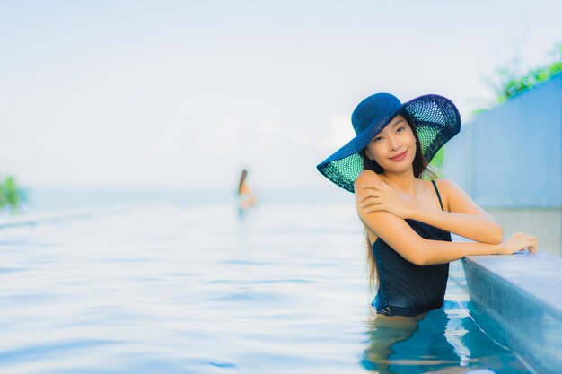 Glückliches Lächeln der schönen jungen asiatischen Frauen des Porträts entspannen sich Swimmingpool im Freien im Hotel