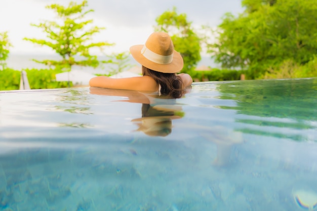 Kostenloses Foto glückliches lächeln der schönen jungen asiatischen frauen des porträts entspannen sich um swimmingpool im freien im hotel