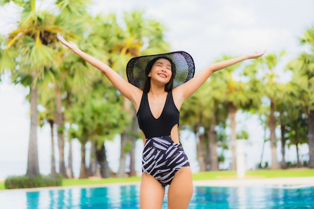 Glückliches Lächeln der schönen jungen asiatischen Frauen des Porträts entspannen sich um Swimmingpool