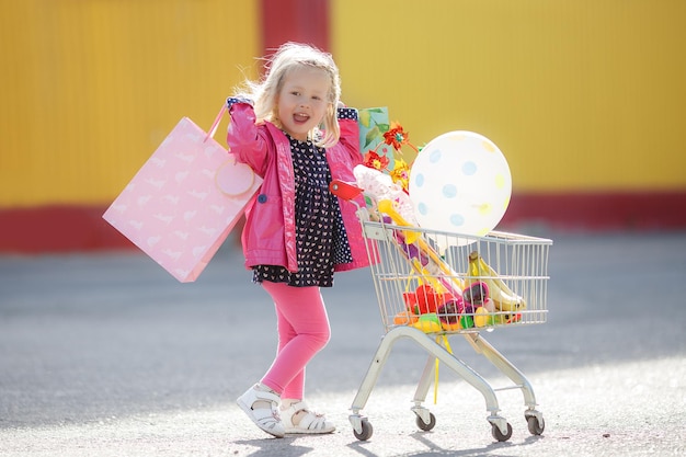 Glückliches lächelndes Kindereinkaufen Kind mit Wagen
