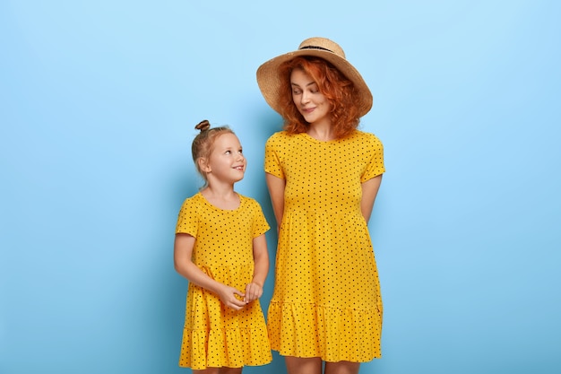 Glückliches liebendes Familienkonzept. Rothaarige Mama in modischem Hut und gelbem Kleid