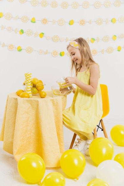 Kostenloses Foto glückliches mädchen am tisch, das limonade gießt