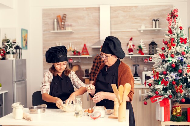 Glückliches Mädchen am Weihnachtstag mit Schürze, die Kekse macht