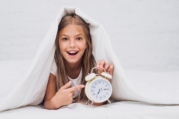 Kostenloses Foto glückliches mädchen, das auf die uhr zeigt