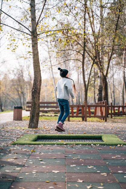 Glückliches Mädchen, das auf ein kleines Trampolin im Park springt