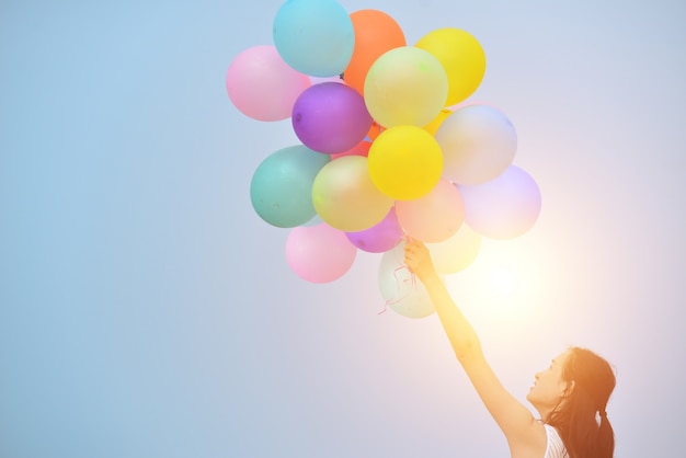 Glückliches Mädchen, das ein Bündel von Luftballons