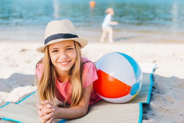 Kostenloses Foto glückliches mädchen, das mit ball an der küste grinst