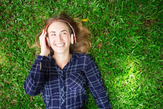 Glückliches Mädchen, das Musik auf Gras zuhört