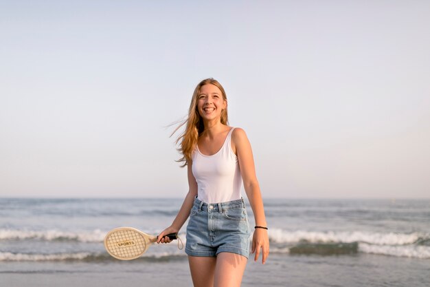 Glückliches Mädchen, das Tennis nahe dem Meer spielt