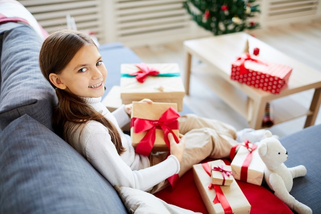 Glückliches Mädchen, das Weihnachtsgeschenke auspackt