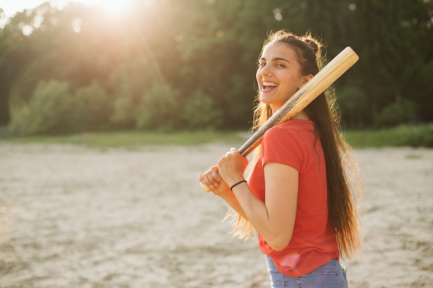Kostenloses Foto glückliches mädchen der seitenansicht, das baseballschläger hält