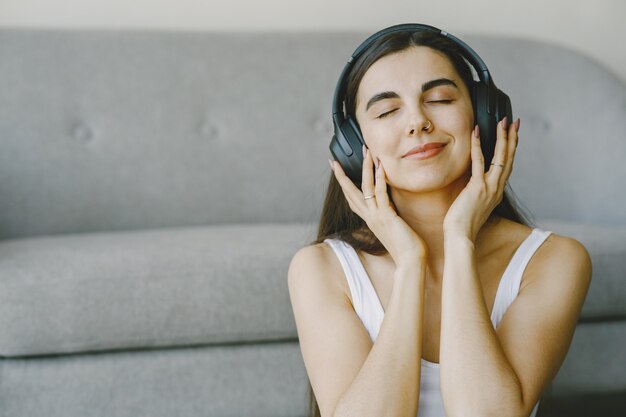 Glückliches Mädchen in den Kopfhörern hört Musik zu Hause